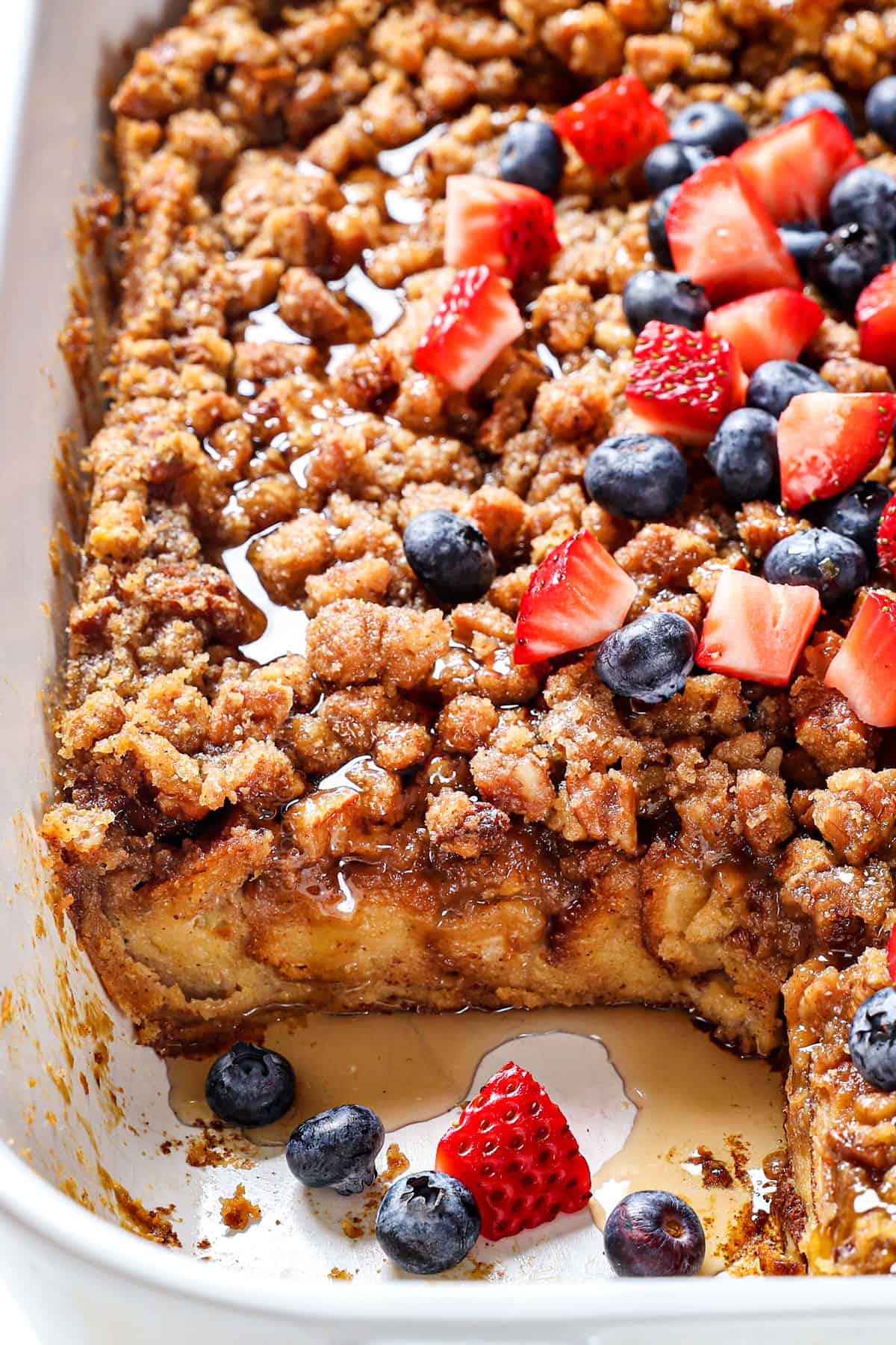 Baked French Toast Recipe in a 9x13 baking dish served with berries, syrup and pecans