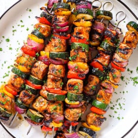 showing how to serve oven chicken kabobs on a platter garnished with parsley