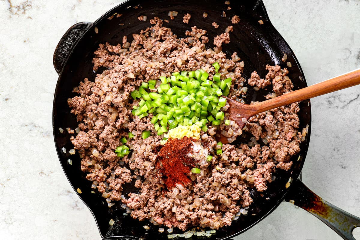 showing how to make sloppy joes by add bell peppers and garlic to ground beef