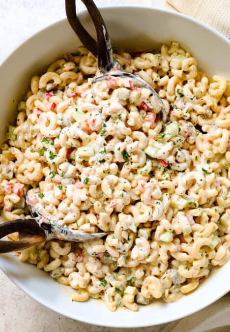 showing how to make macaroni salad recipe by tossing the salad dressing with the salad ingredients until creamy
