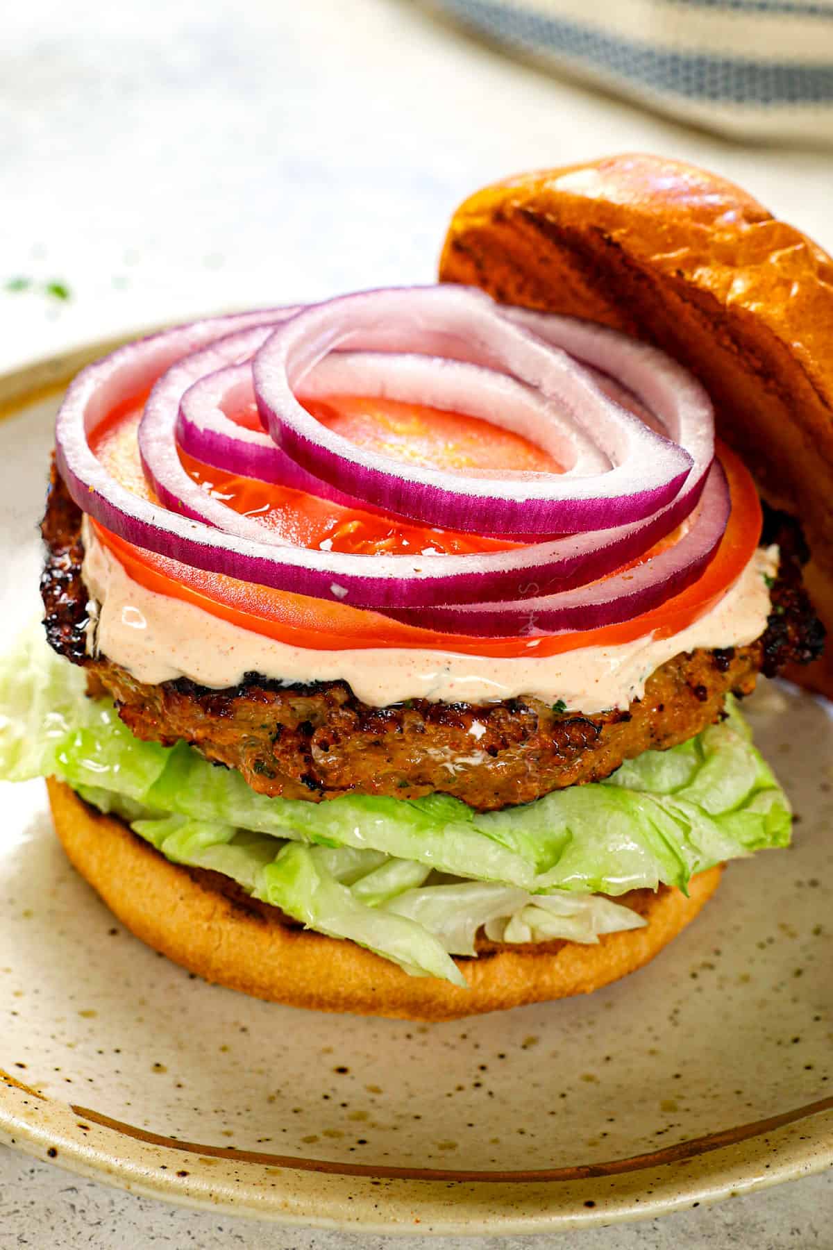 best turkey burger recipe served on a plate with tomatoes, lettuce and onion