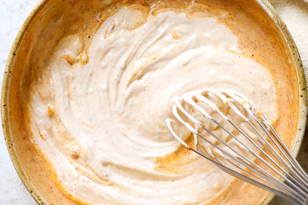 showing how to make remoulade by whisking the ingredients together in a bowl until creamy
