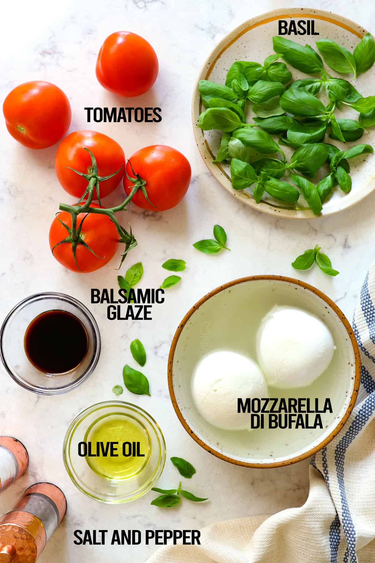 showing how to make Caprese Salad by laying out ingredients: tomatoes, basil, mozzarella, olive oil, salt and pepper