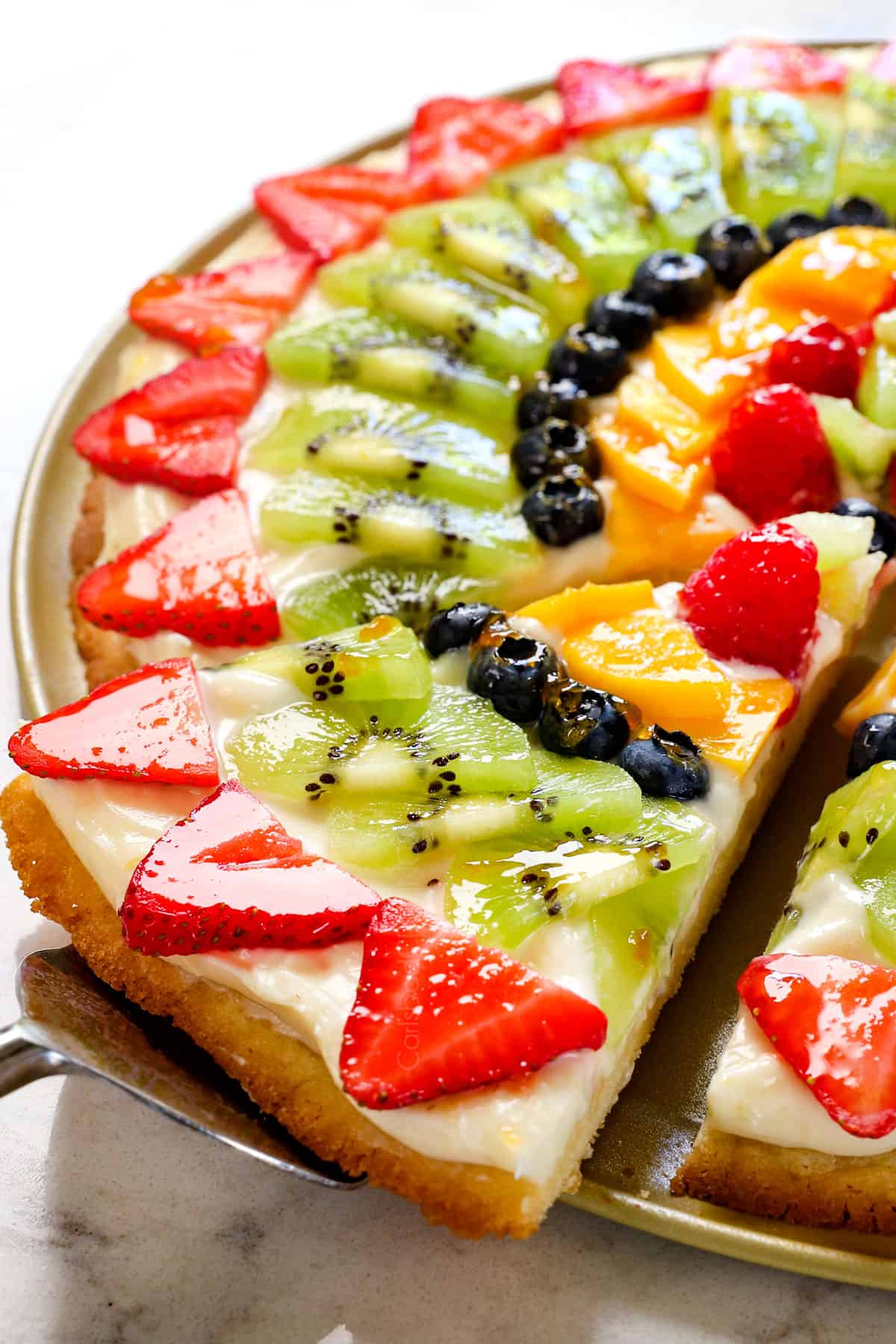 up close of fruit pizza showing a slice being served