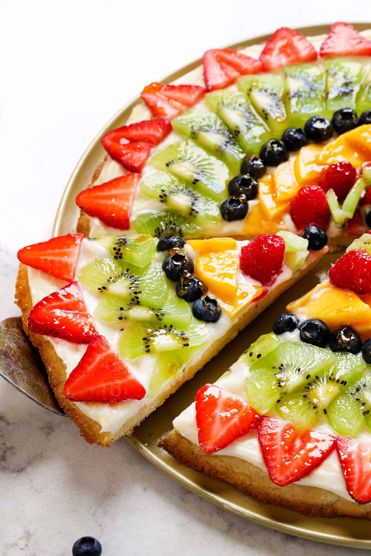 showing how to serve fruit pizza by cutting into slices