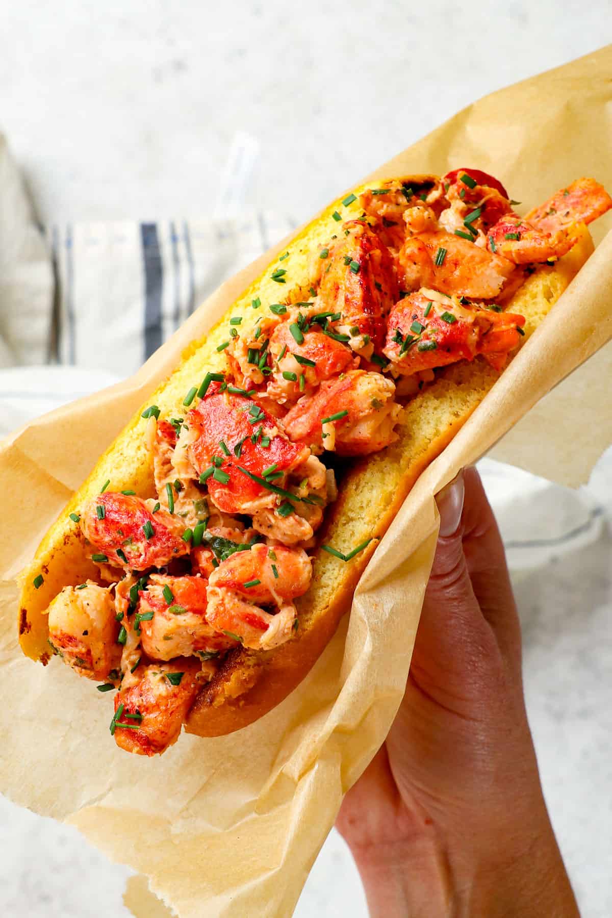 up closer of holding a lobster roll showing the juicy lobster meat