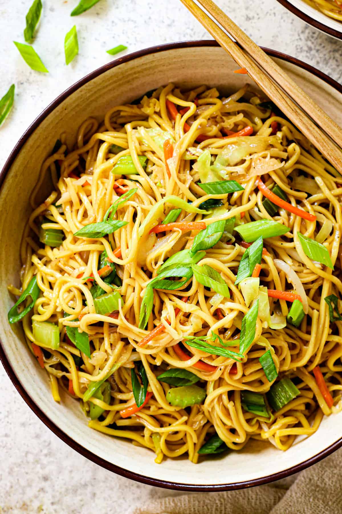 showing how to serve chow mein recipe easy in a bowl garnished by green onions