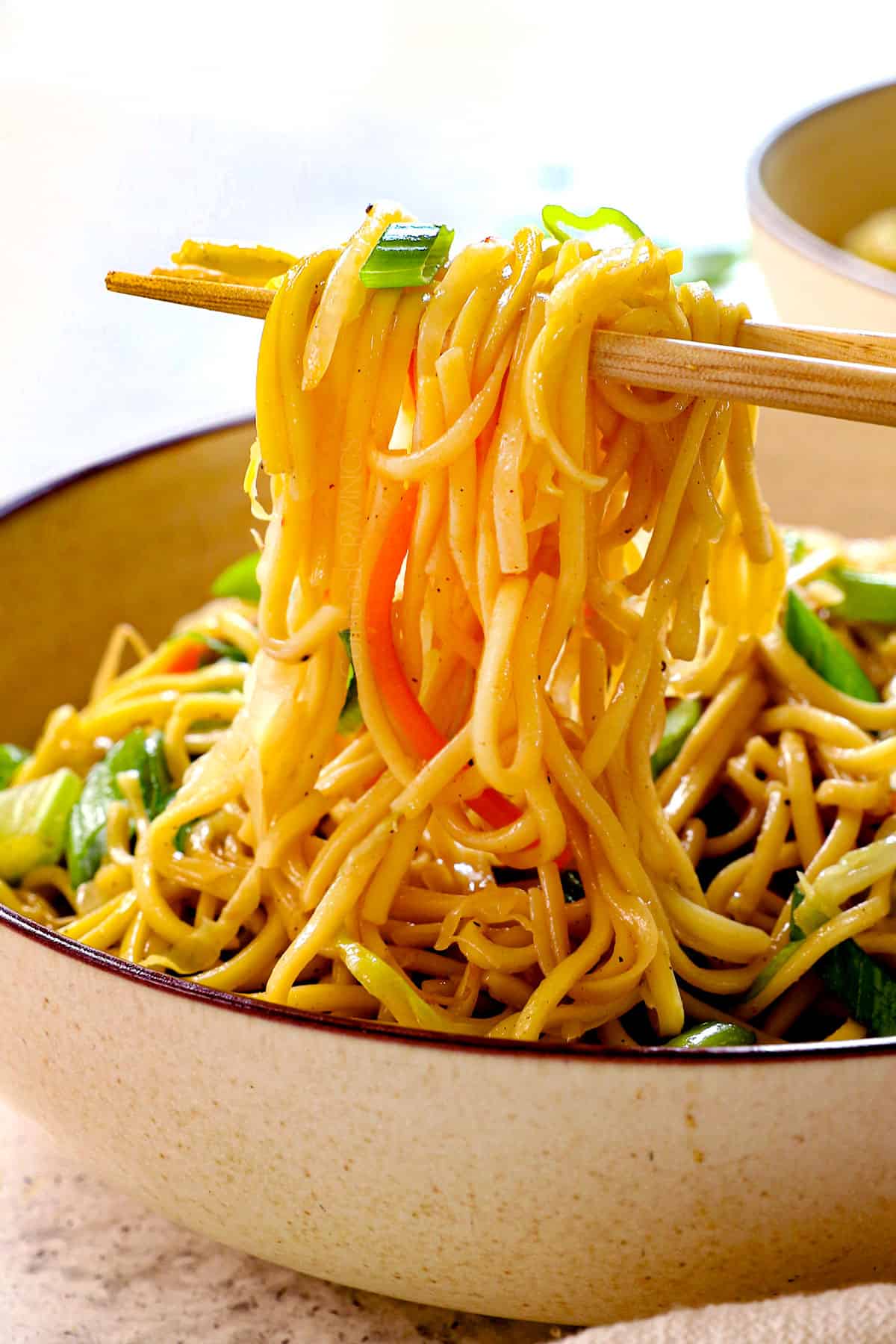 eating chow mein with chopsticks from a bowl