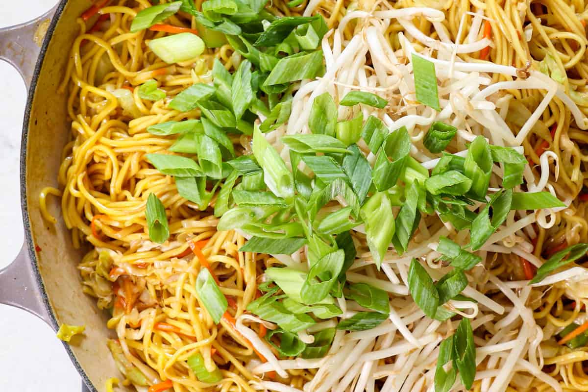 showing how to make chow mein by adding bean sprouts and green onions and stir frying