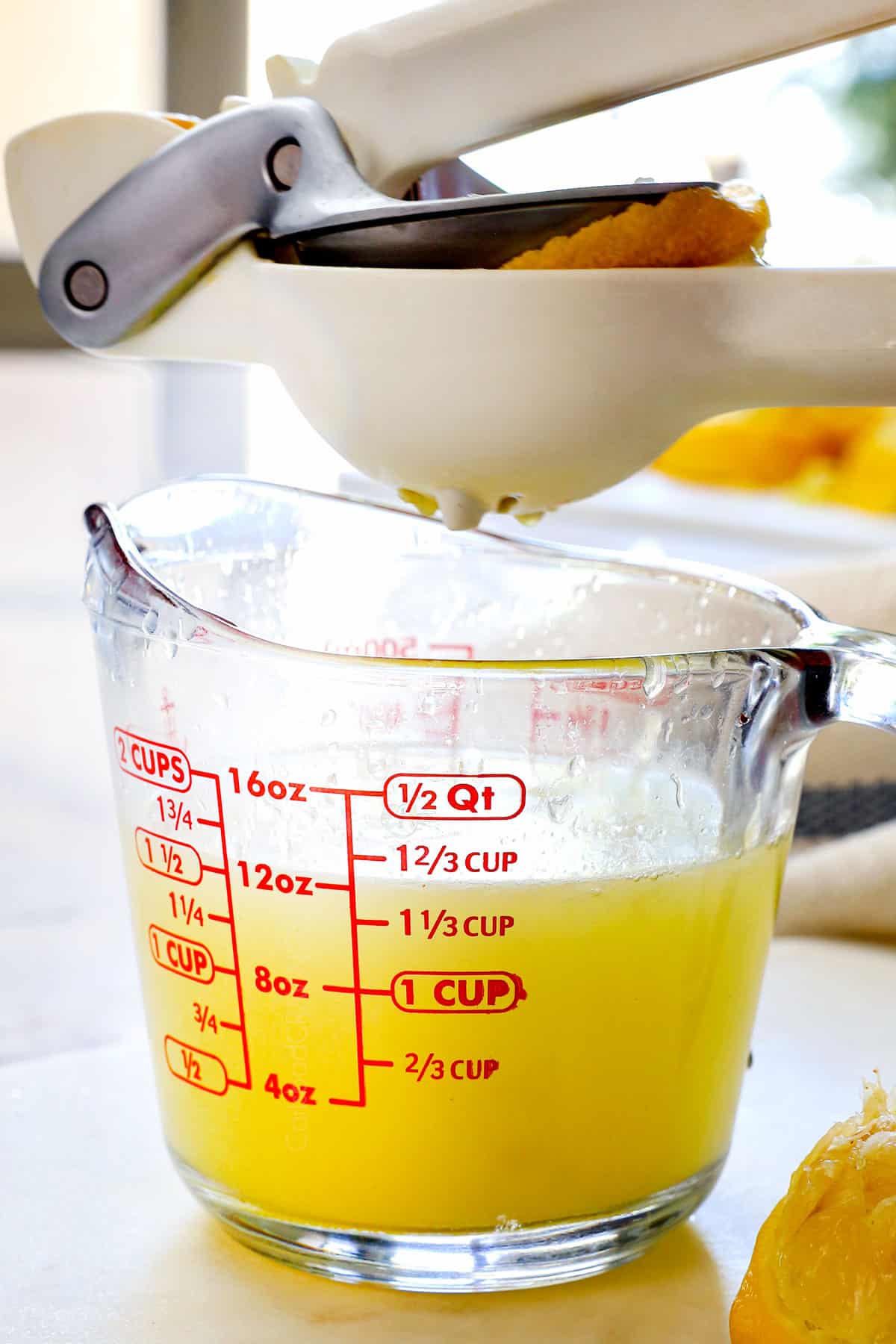 showing how to make homemade lemonade by juicing lemons into a liquid measuring cup