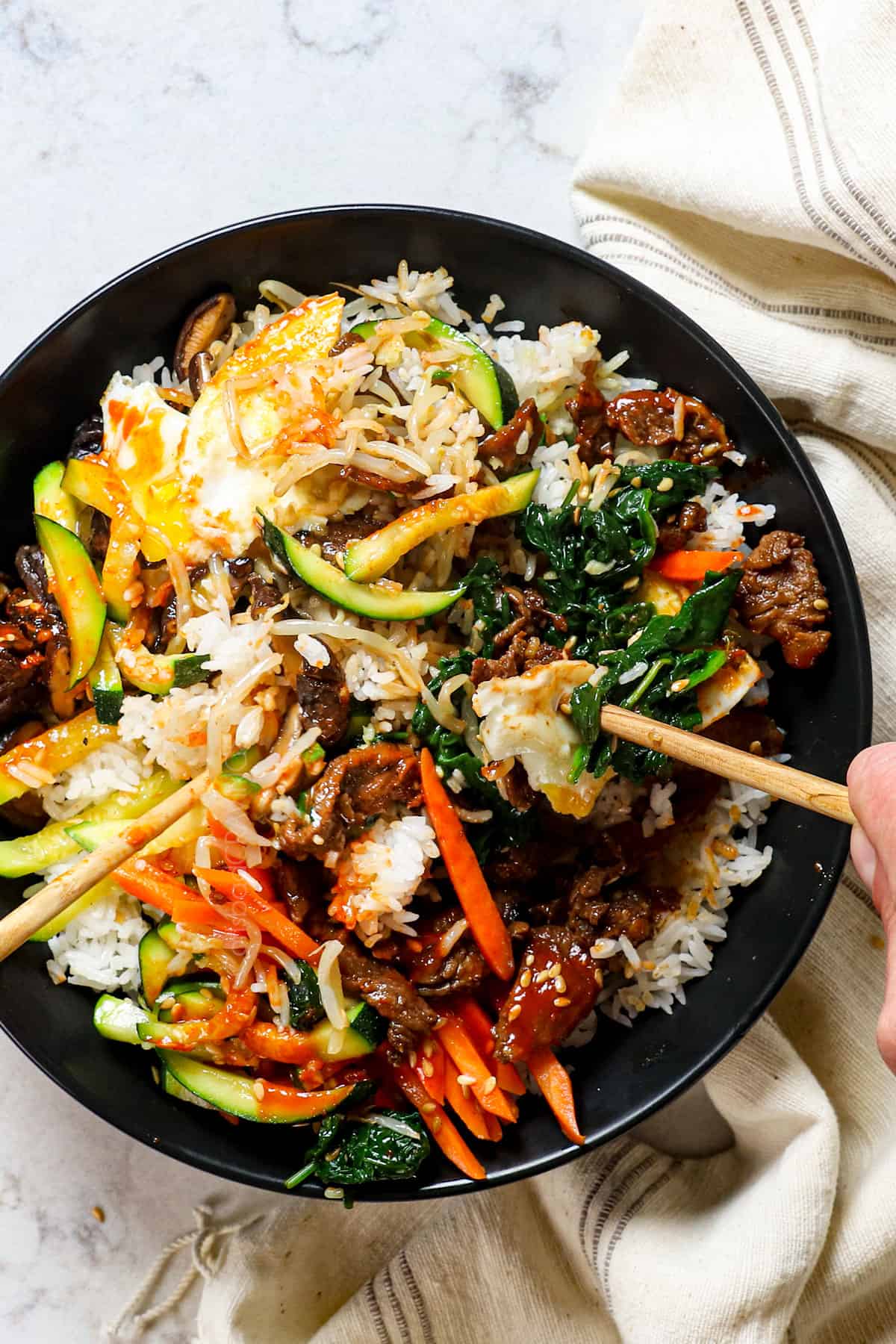 showing how to eat bibimbap by tossing the ingredients together with chopsticsk