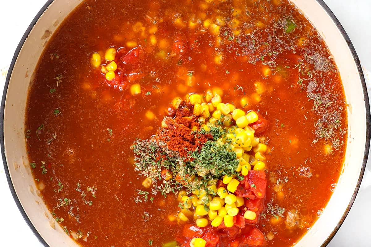 showing how to make goulash by adding tomato sauce, corn and seasonings to the pot