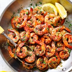 showing how to make Cajun shrimp recipe by tossing sautéed shrimp with butter and parsley