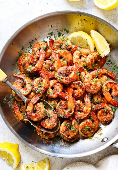 showing how to make Cajun shrimp recipe by tossing sautéed shrimp with butter and parsley