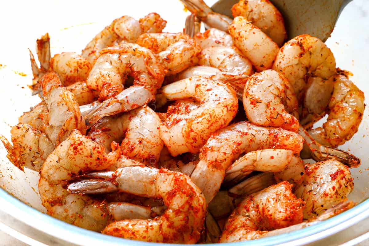 showing how to make Cajun shrimp by tossing shrimp with Cajun seasoning for shrimp