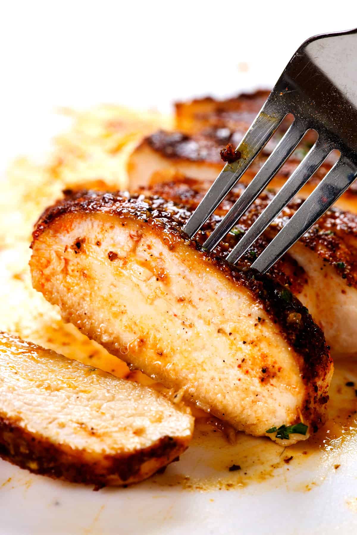 a fork picking up juicy baked chicken breast