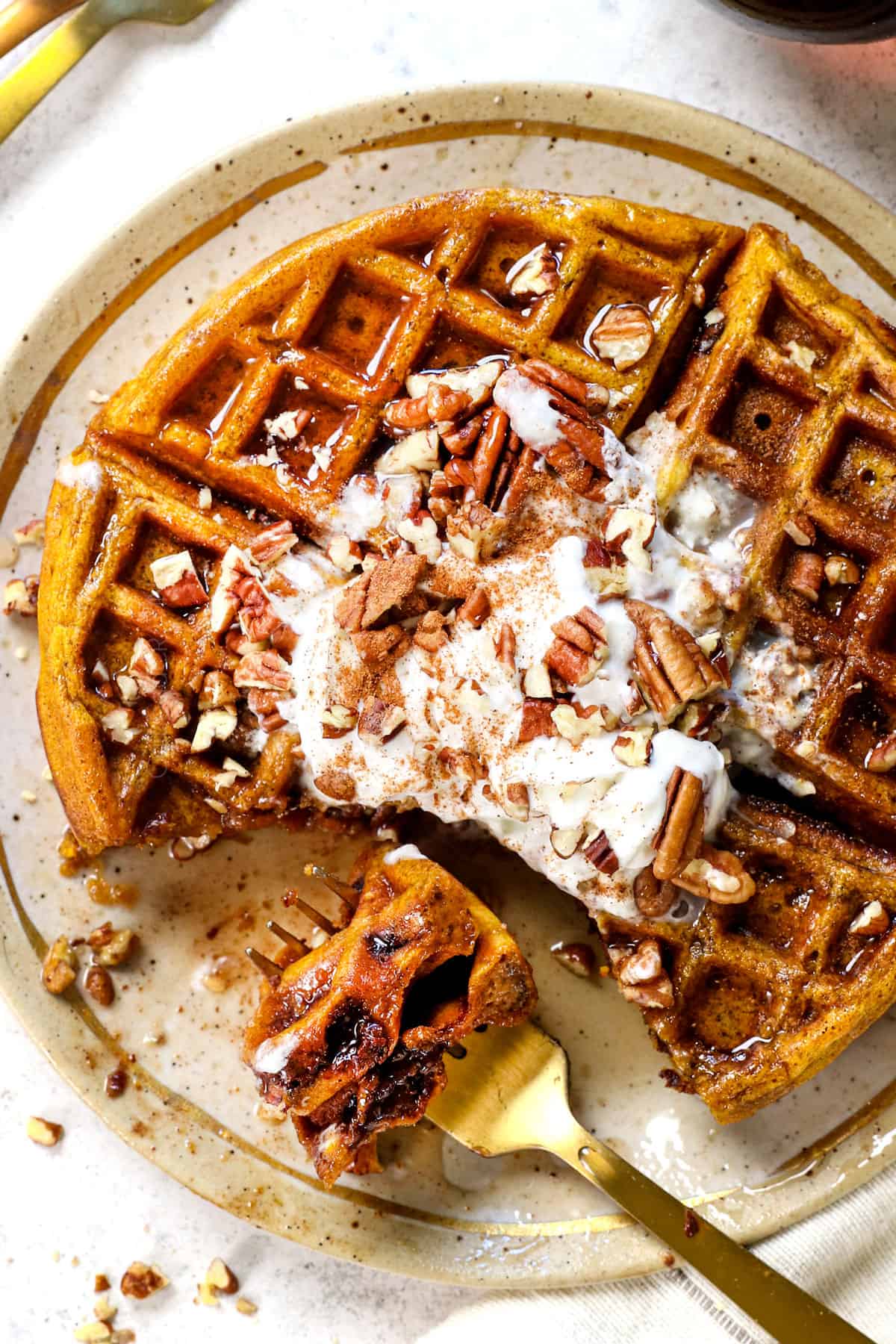 top view showing how to make serve pumpkin waffles on a plate topped with chopped pecans