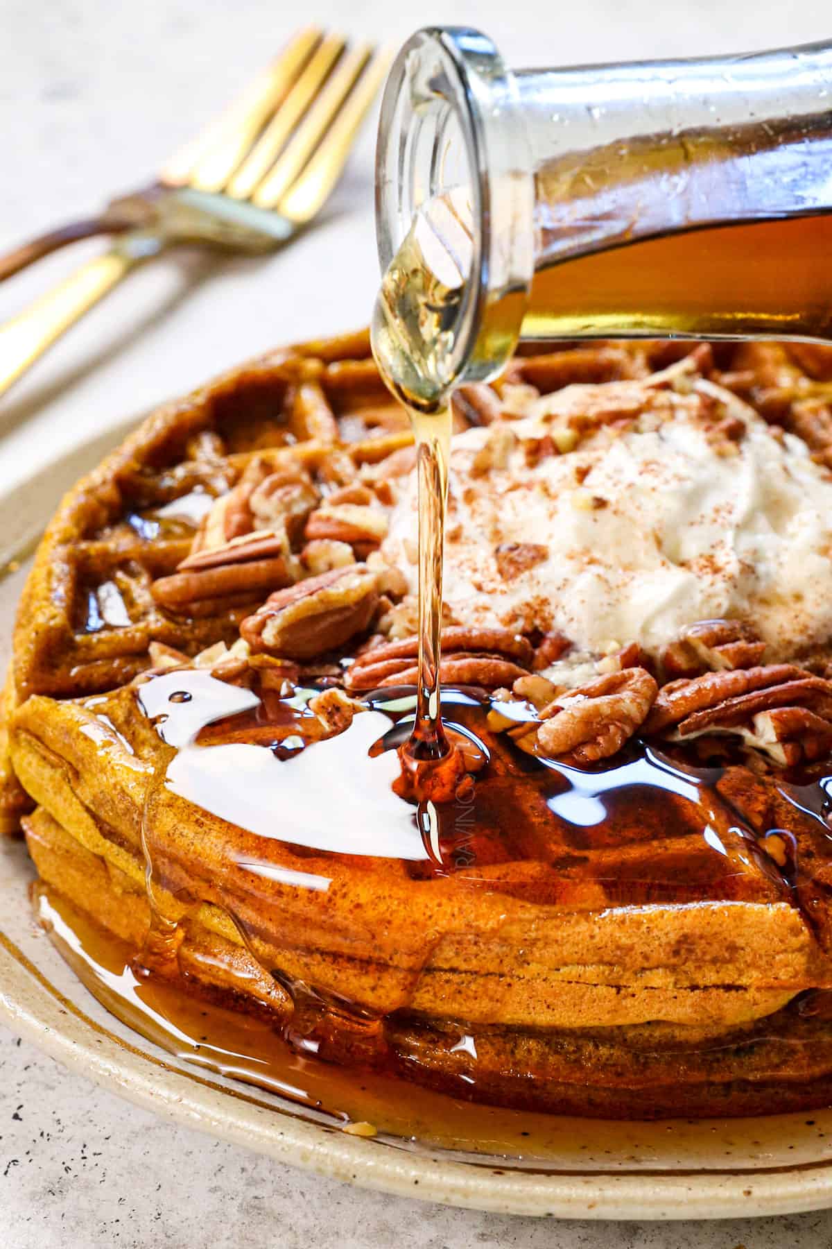 showing how to serve pumpkin spice waffles by pouring maple syrup over top