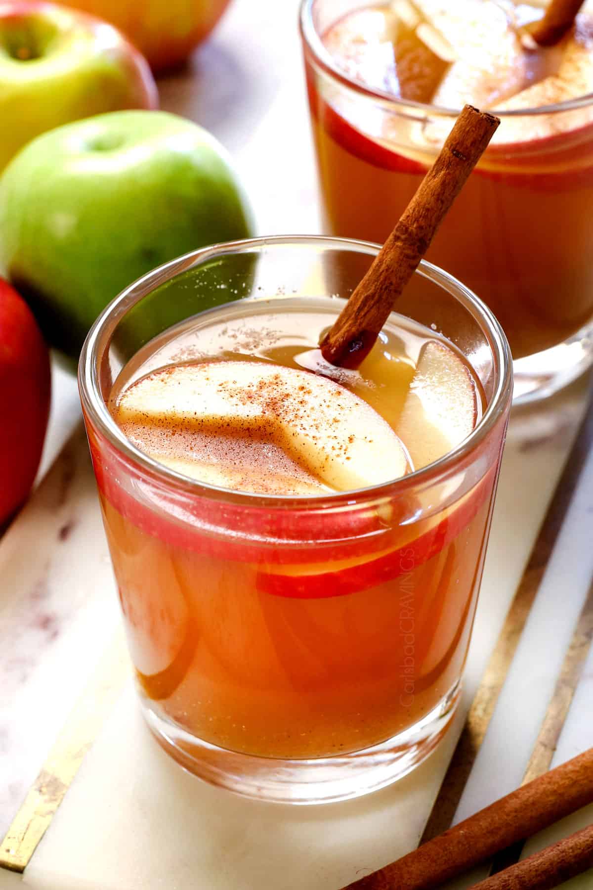 serving apple cider hot in a glass with a cinnamon stick