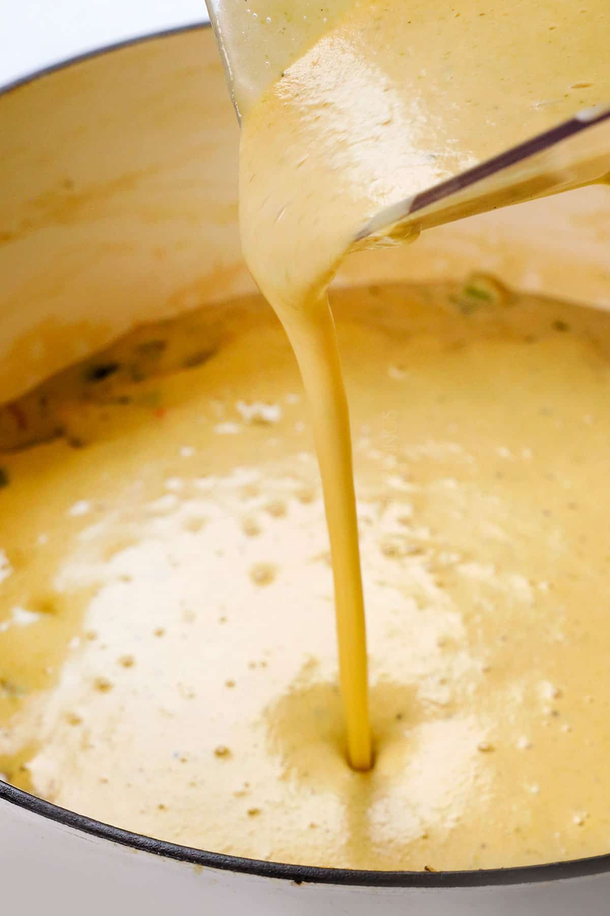 showing how to make potato soup by pouring pureed soup back into the soup pot