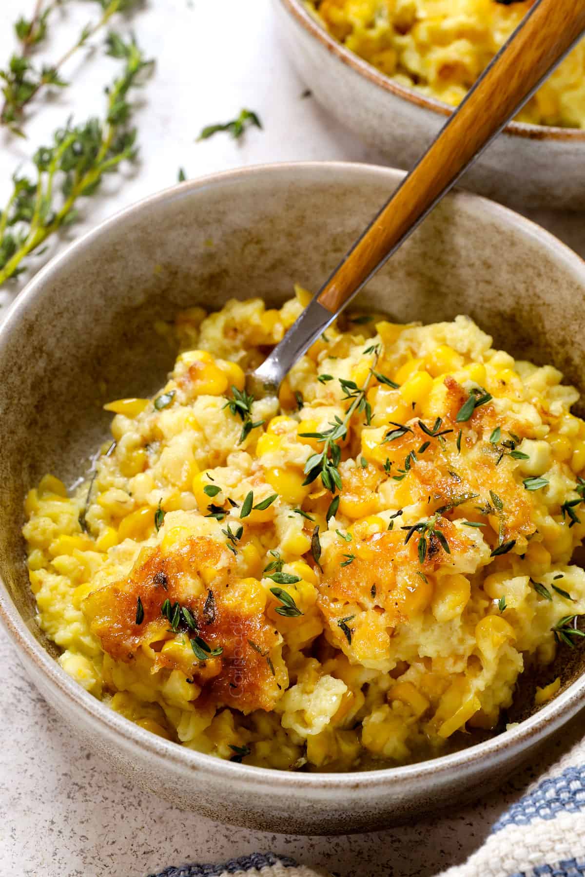 up close of recipe for corn casserole in an individual bowl garnished with thyme