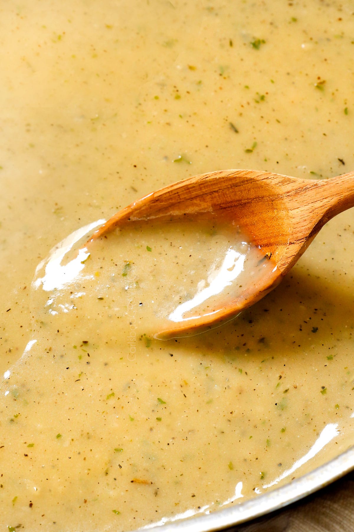 spooning turkey gravy recipe in a pan showing it's smooth consitency