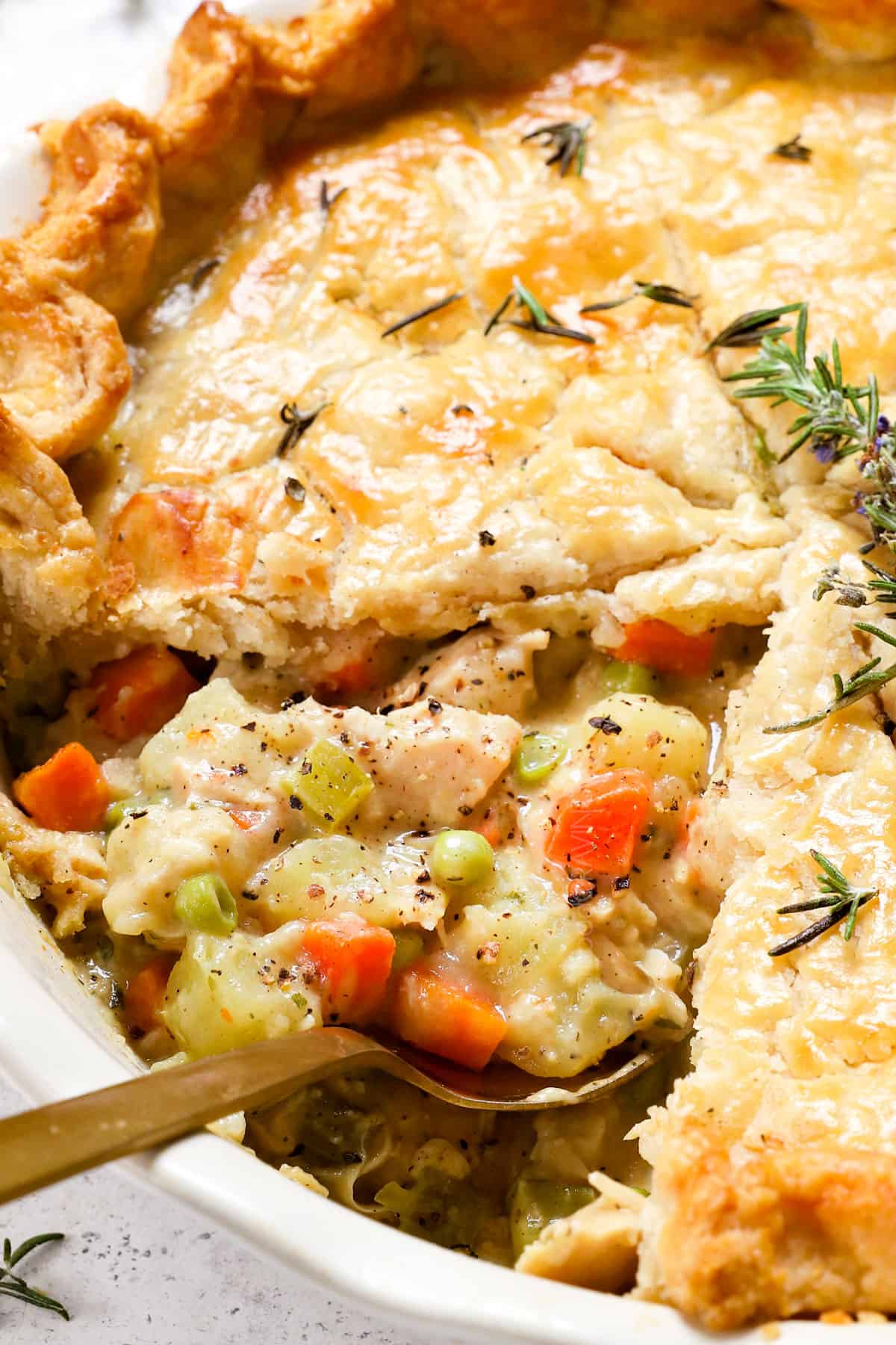 turkey pot pie with a spoon in the filling showing the carrots, celery, peas and turkey