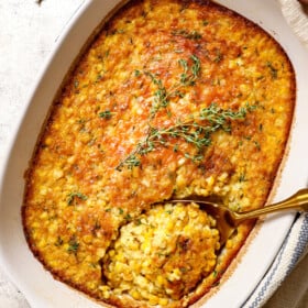 two hands holding corn pudding casserole to serve