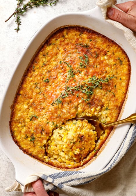 two hands holding corn pudding casserole to serve