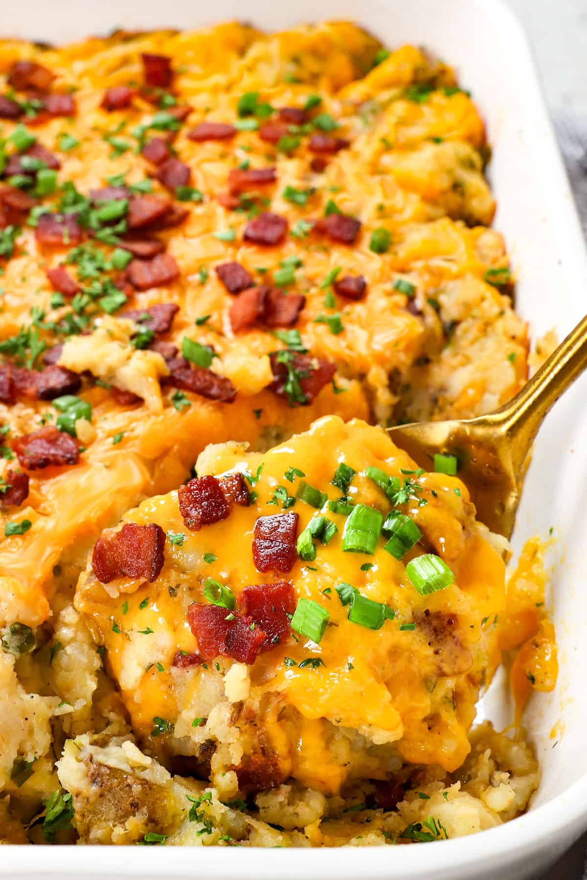 serving twice baked potato casserole with cheddar cheese, green onions and bacon 