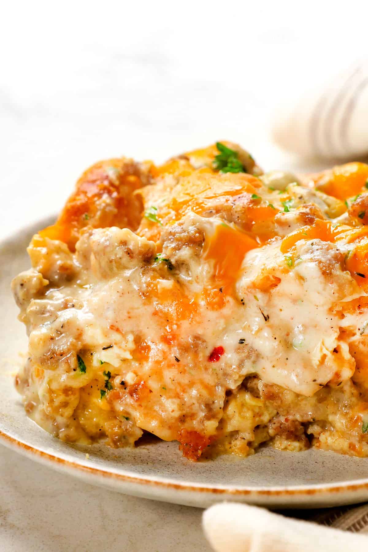 up close of a slice of sausage gravy casserole showing how creamy and cheesy it is