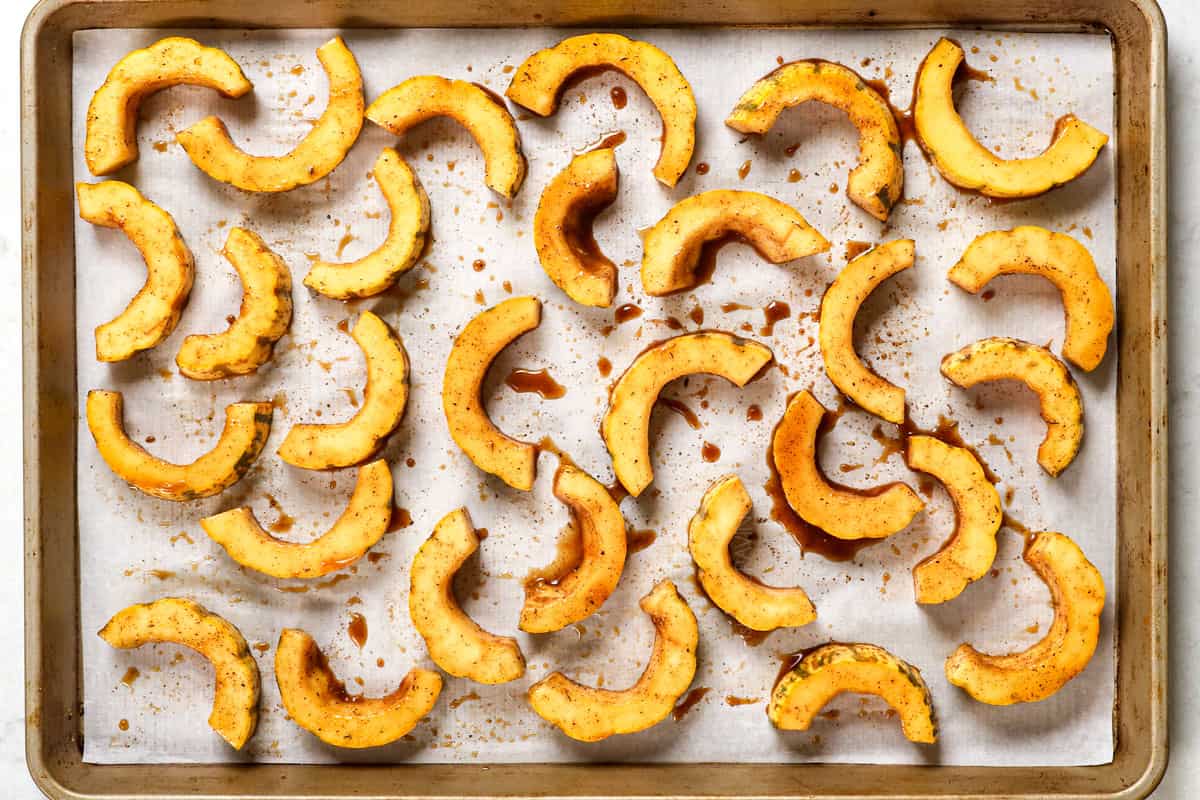 showing how to cook delicata squash by lining the half moons in a single layer on a baking sheet