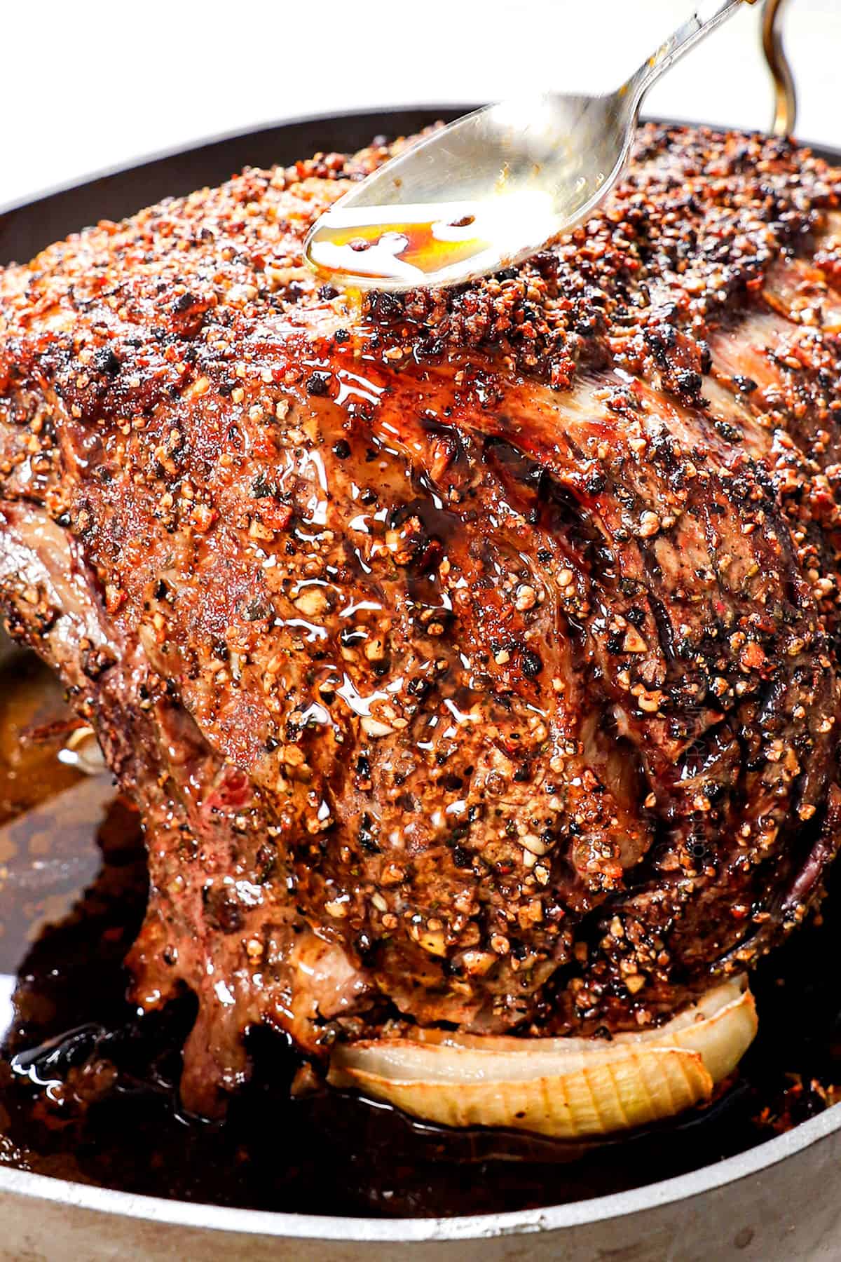 showing how to cook prime rib by basting with pan juices after roasting