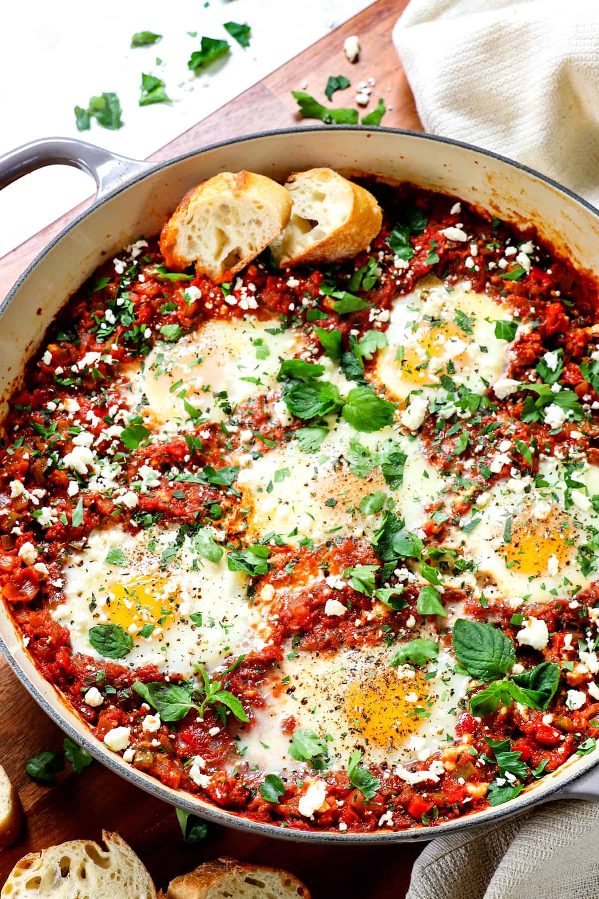 showing shakshuka recipe in a cast iron enameled pan garnished with cilantro and feta
