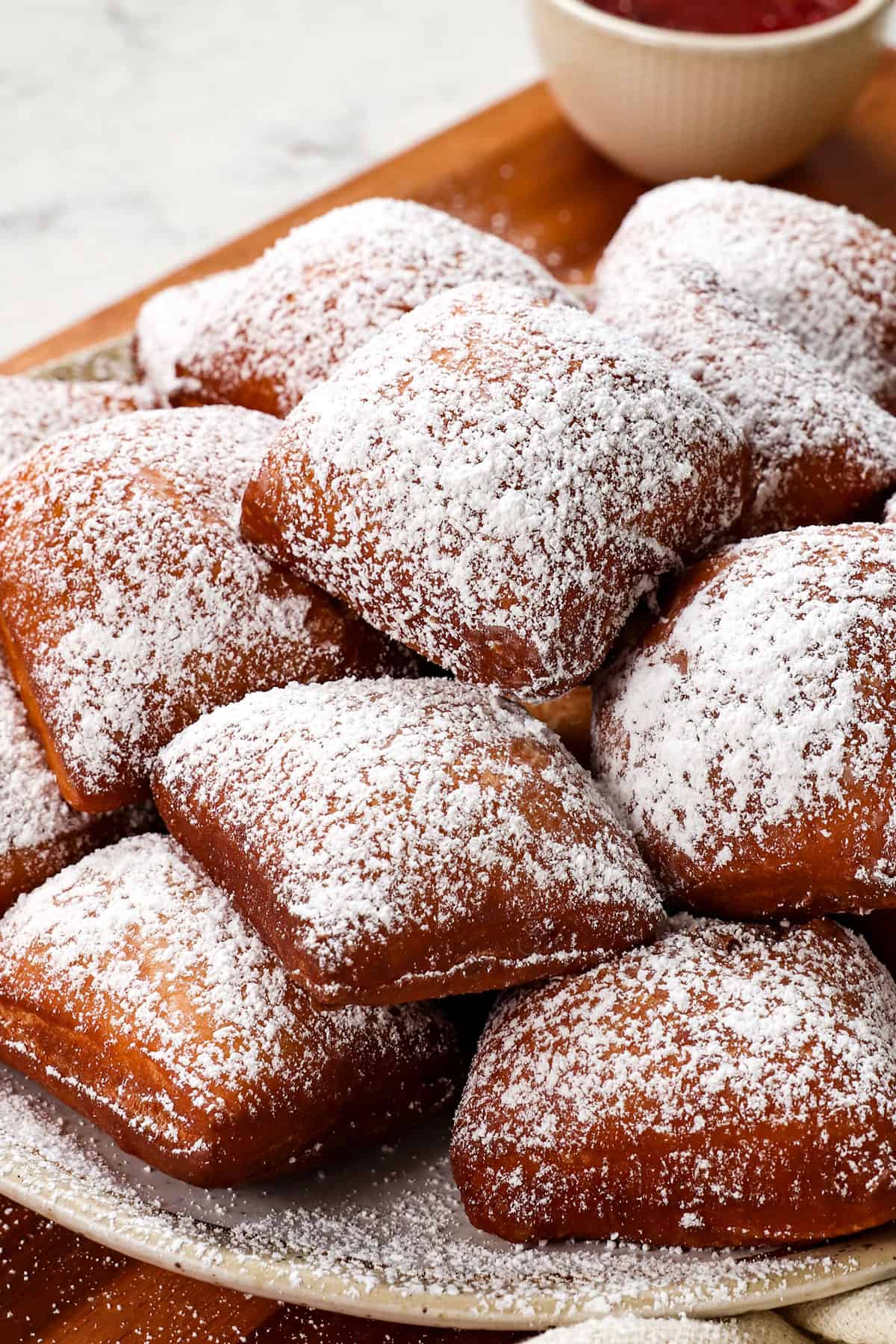 a plate of homemade beignets showing how thick and puffy they are
