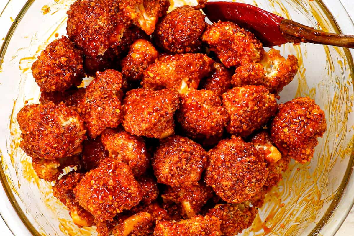 showing how to make buffalo cauliflower by tossing with buffalo hot wings sauce 