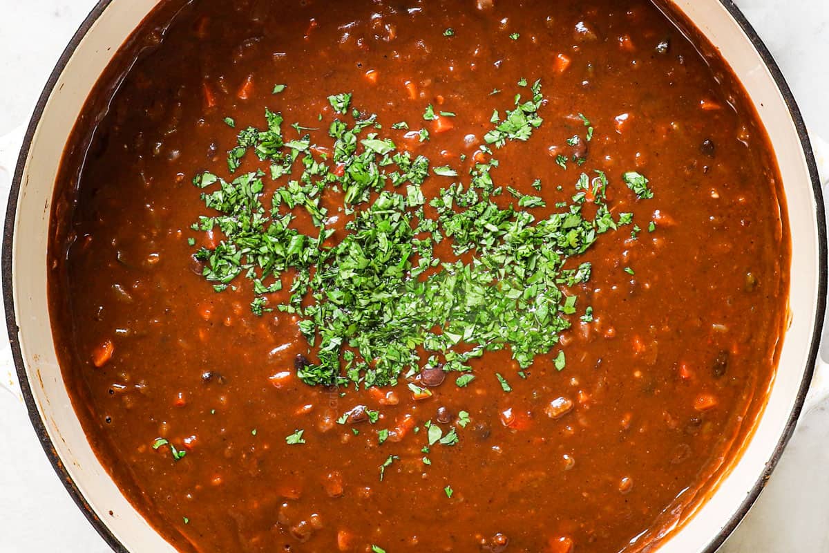showing how to make black bean soup by stirring in cilantro and lime juice