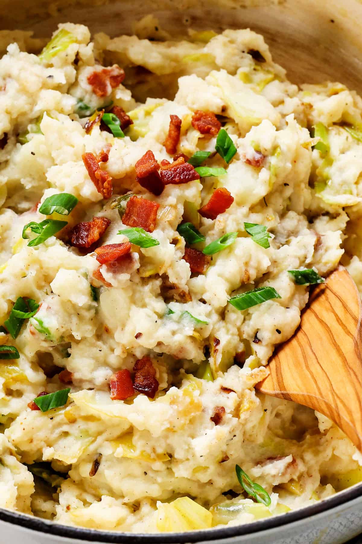 showing how to make colcannon by stirring the potatoes and bacon together