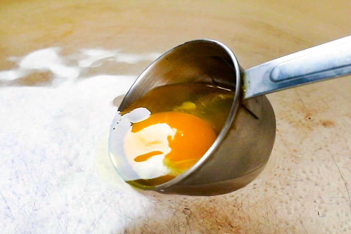 showing how to make Eggs Benedict by rolling egg into the hot water to poach
