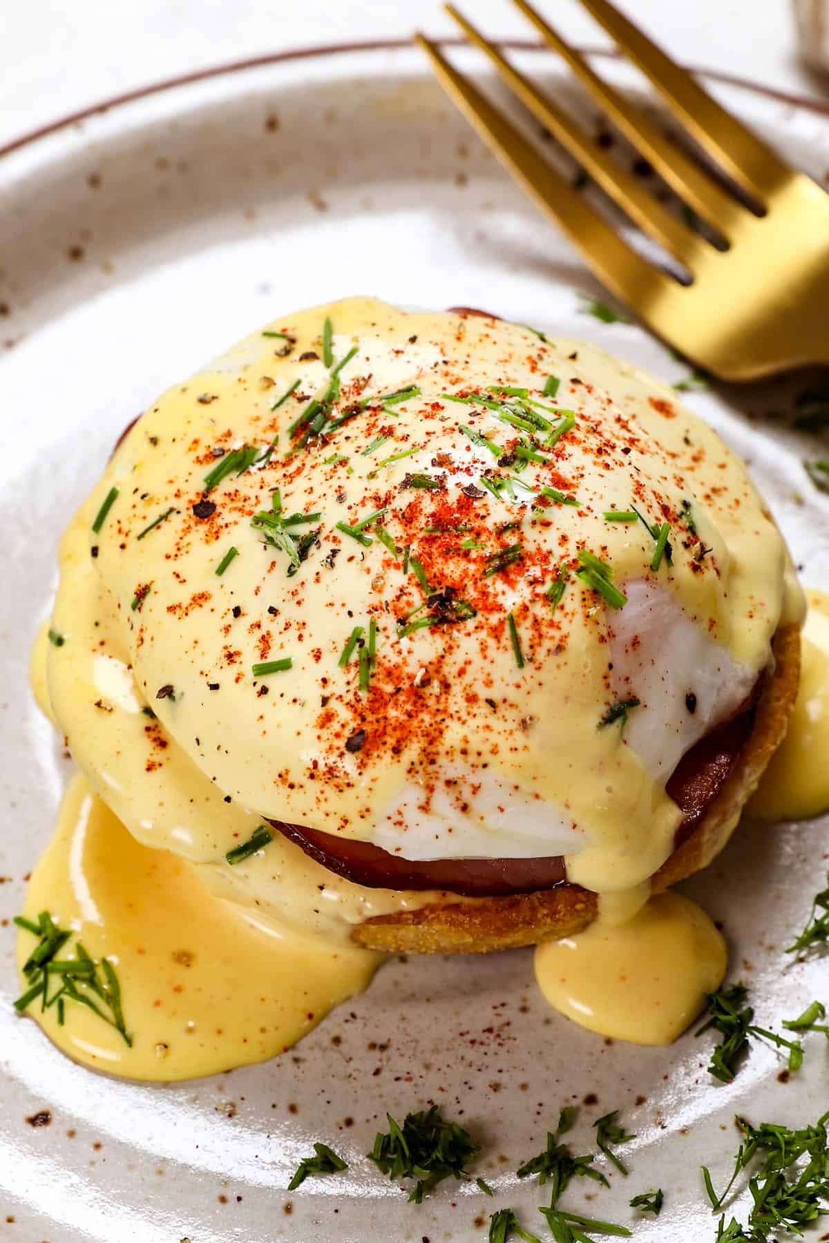 serving egg benedict on a plate with a poached egg and Eggs Benedict sauce