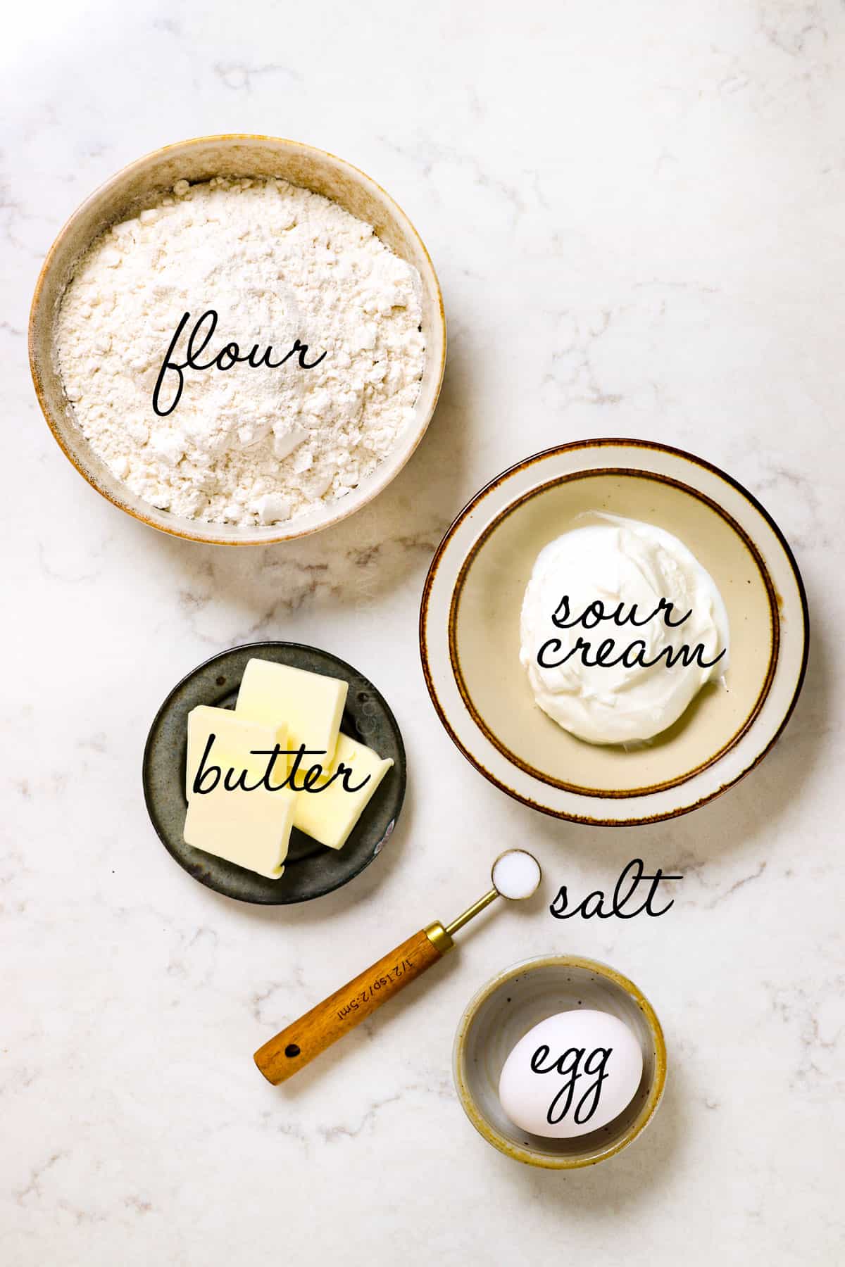 top view showing pierogi dough ingredients: flour, sour cream, butter, salt and egg