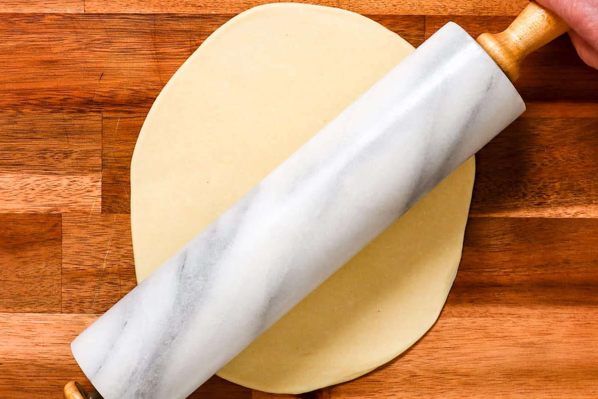 showing how to make pierogi by rolling out pierogi dough on a cutting board