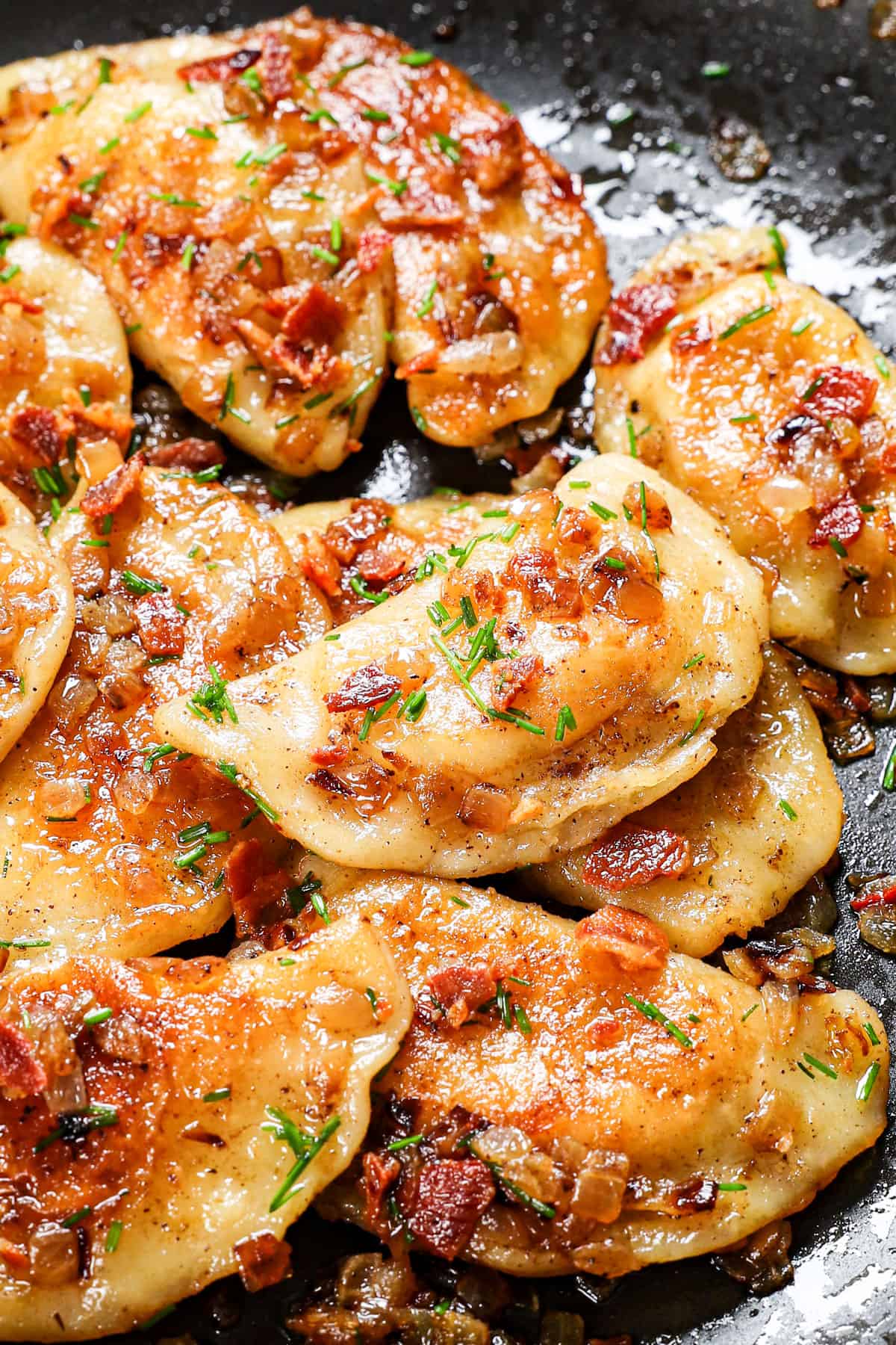 pierogi recipe in a nonstick skillet being tossed with caramelized onions