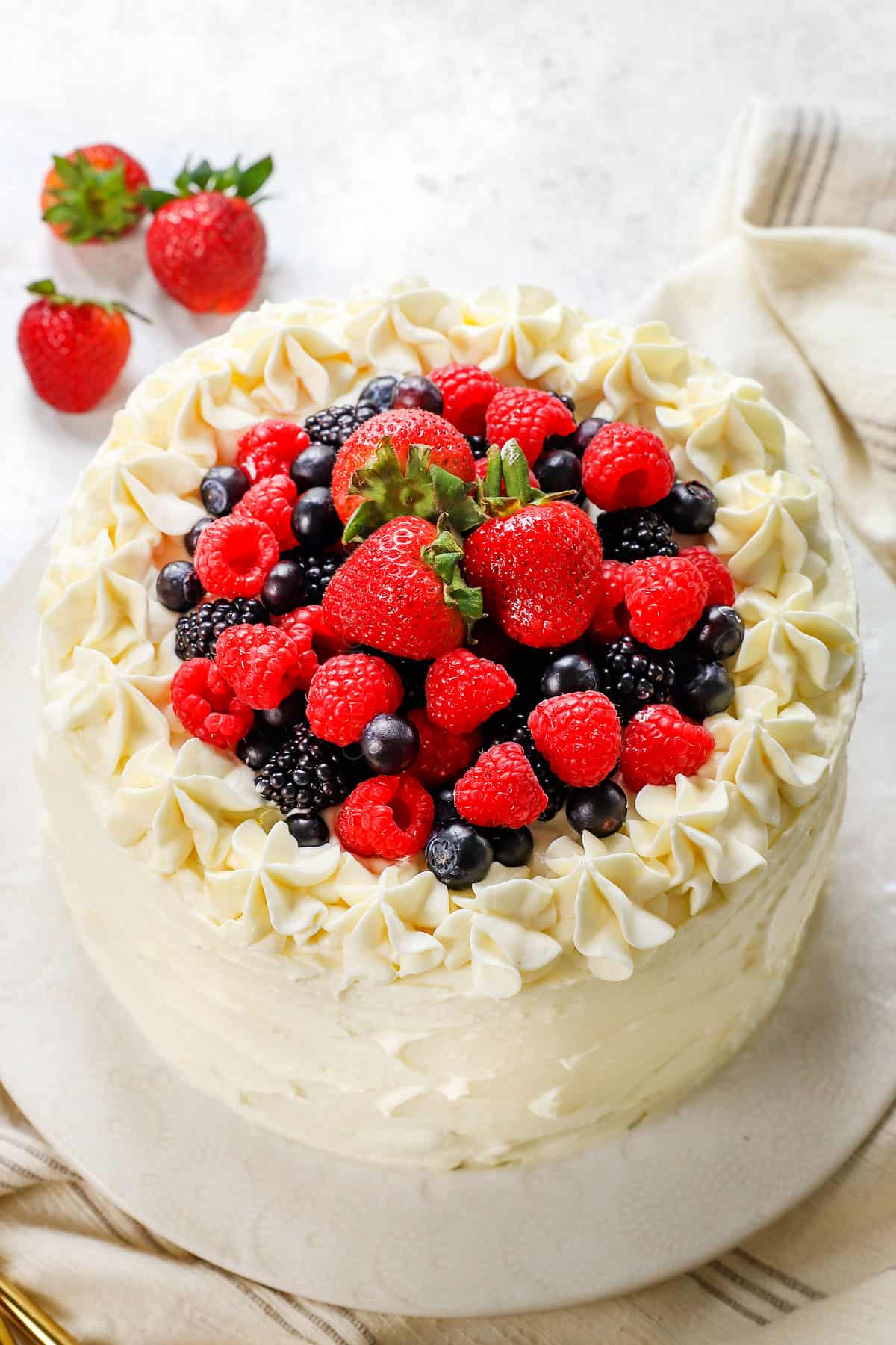 berry Chantilly cake on a platter garnished with berries - showing how to garnish and frosting design