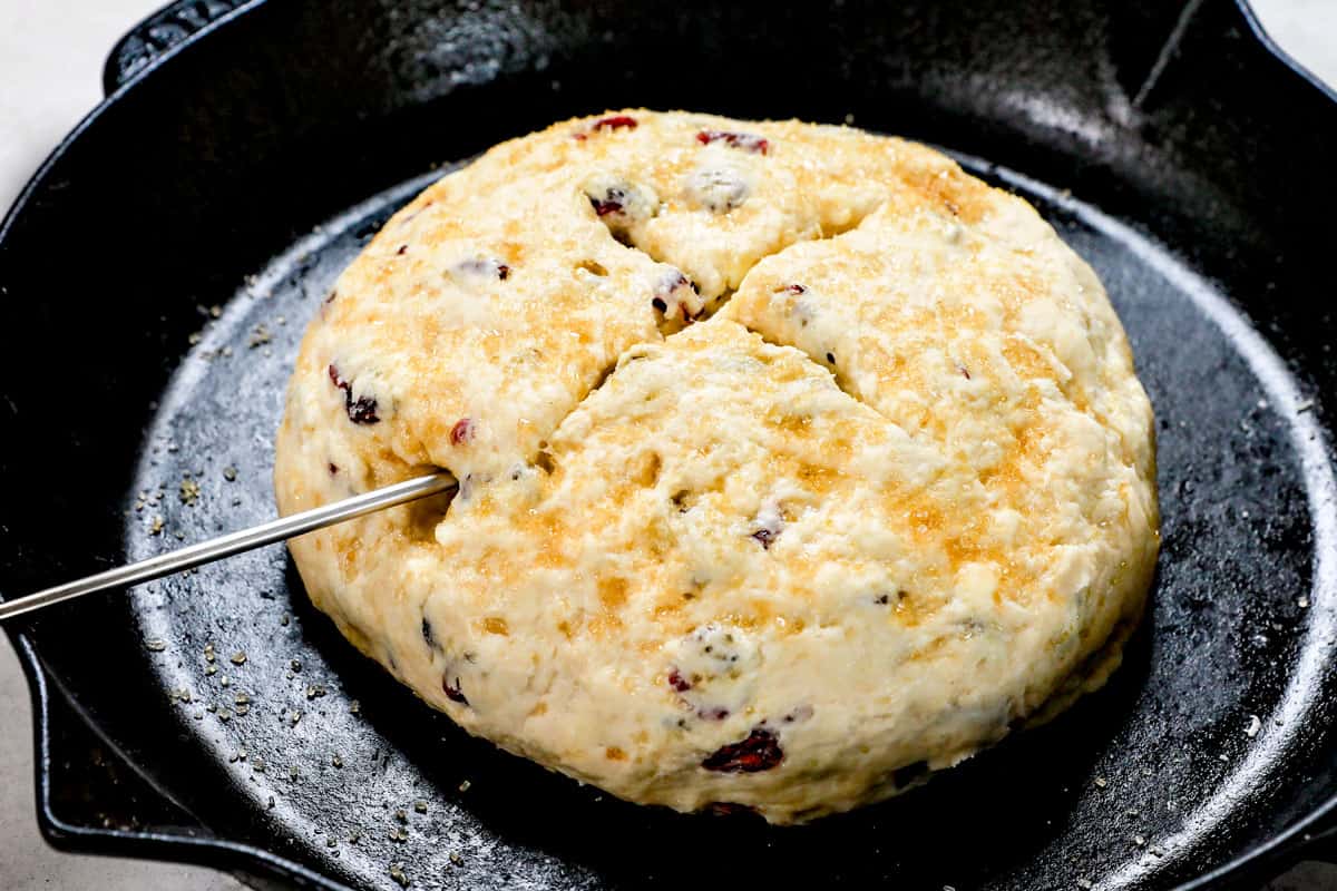 showing how to make Irish soda bread by making an X in the middle of the loaf and placing in a cast iron skillet