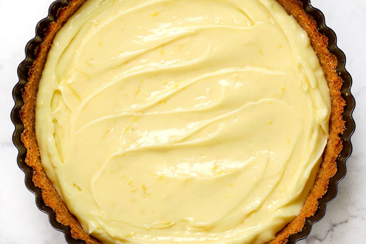 showing how to make lemon pie recipe by adding lemon pie filling to the crust and chilling