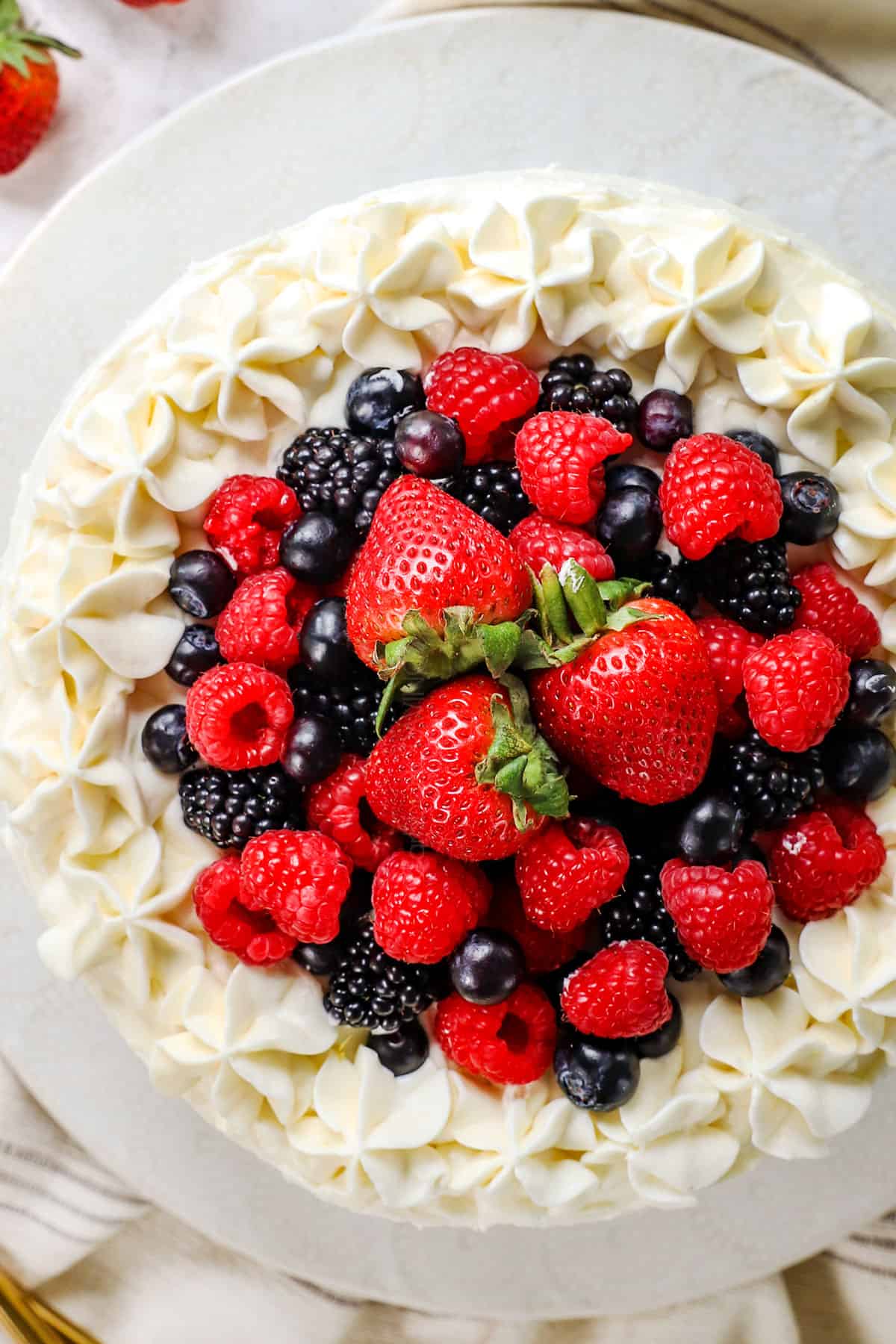showing how to make Chantilly Cake by topping with berries