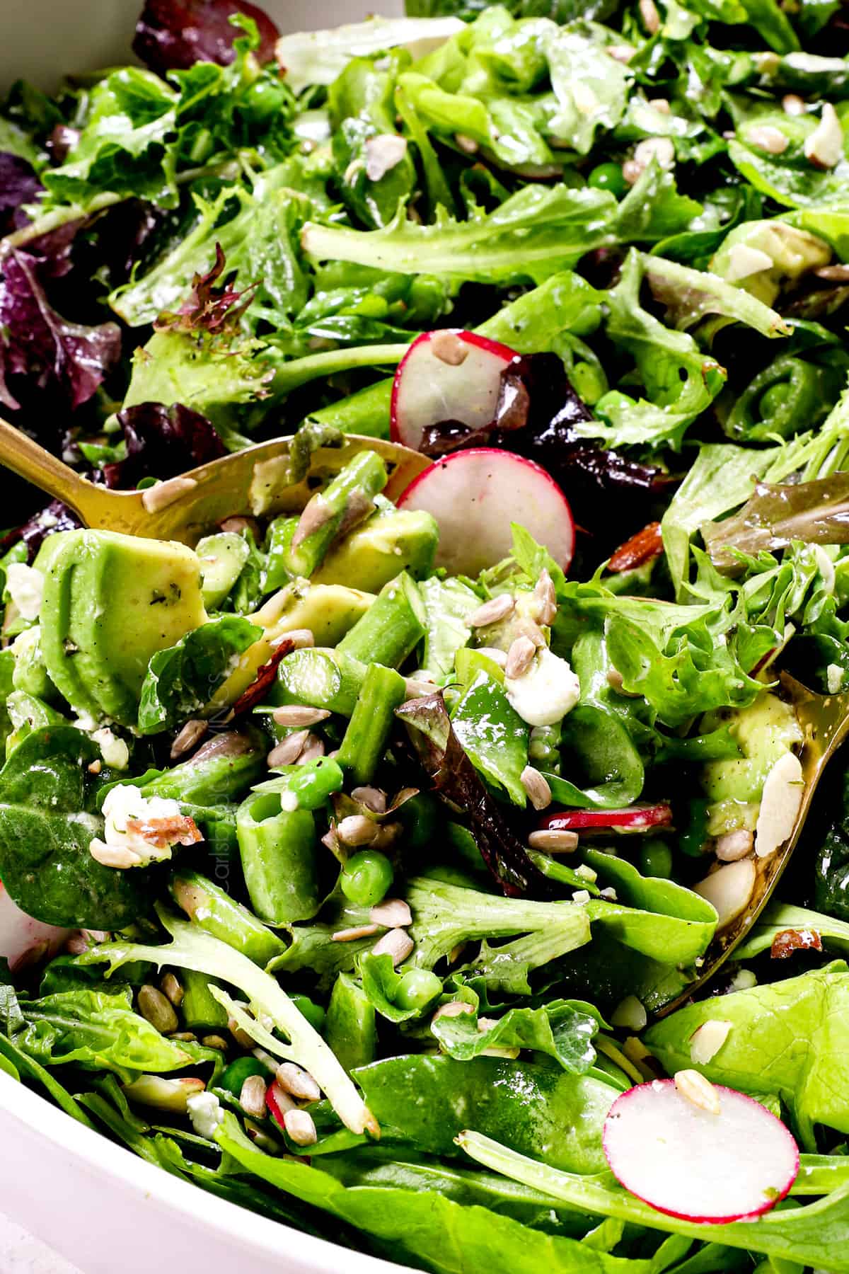 showing how to make spring salad by tossing with dressing