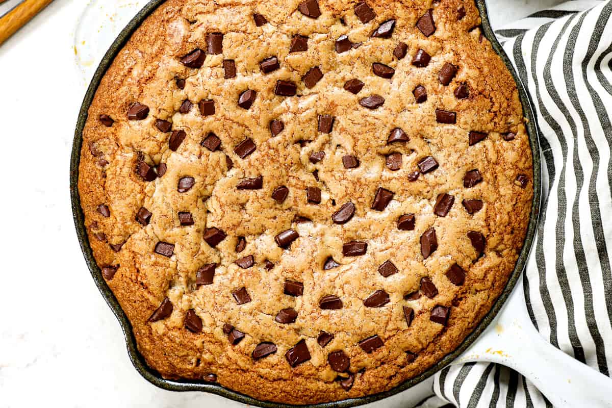 showing how to make pizookie by baking until golden and puffed around the edges