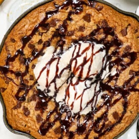 showing how to serve pizookie recipe with chocolate chips drizzled with chocolate sauce